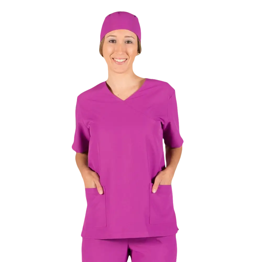 Una donna sorridente con un camice medico color magenta e un berretto abbinato.