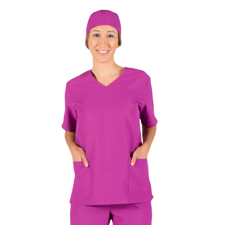 Una donna sorridente con un camice medico color magenta e un berretto abbinato.