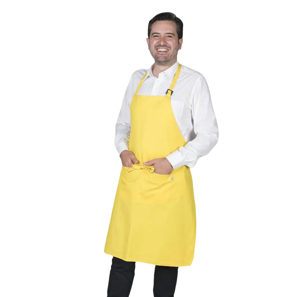 Un uomo sorridente che indossa un grembiule giallo brillante su una camicia bianca e pantaloni scuri.