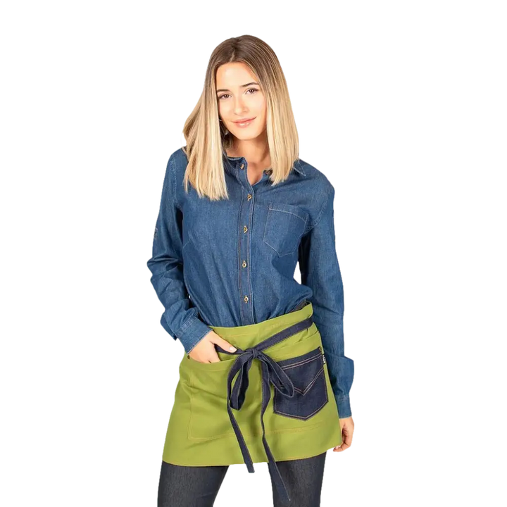 Una donna che indossa una camicia di jeans e un mezzo grembiule verde con tasche blu scuro.