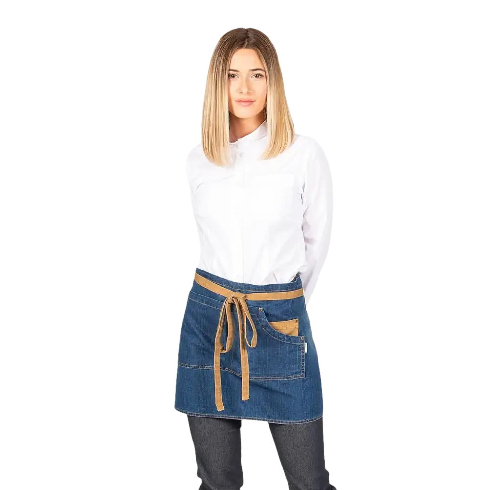 Una donna modella un grembiule corto in denim con cravatta marrone e tasche.